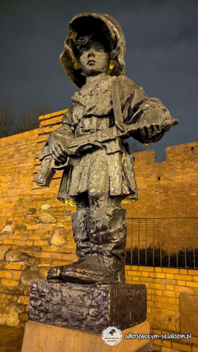 El monumento al Pequeño Insurgente junto a las murallas en la calle Podwale, iluminado por la noche