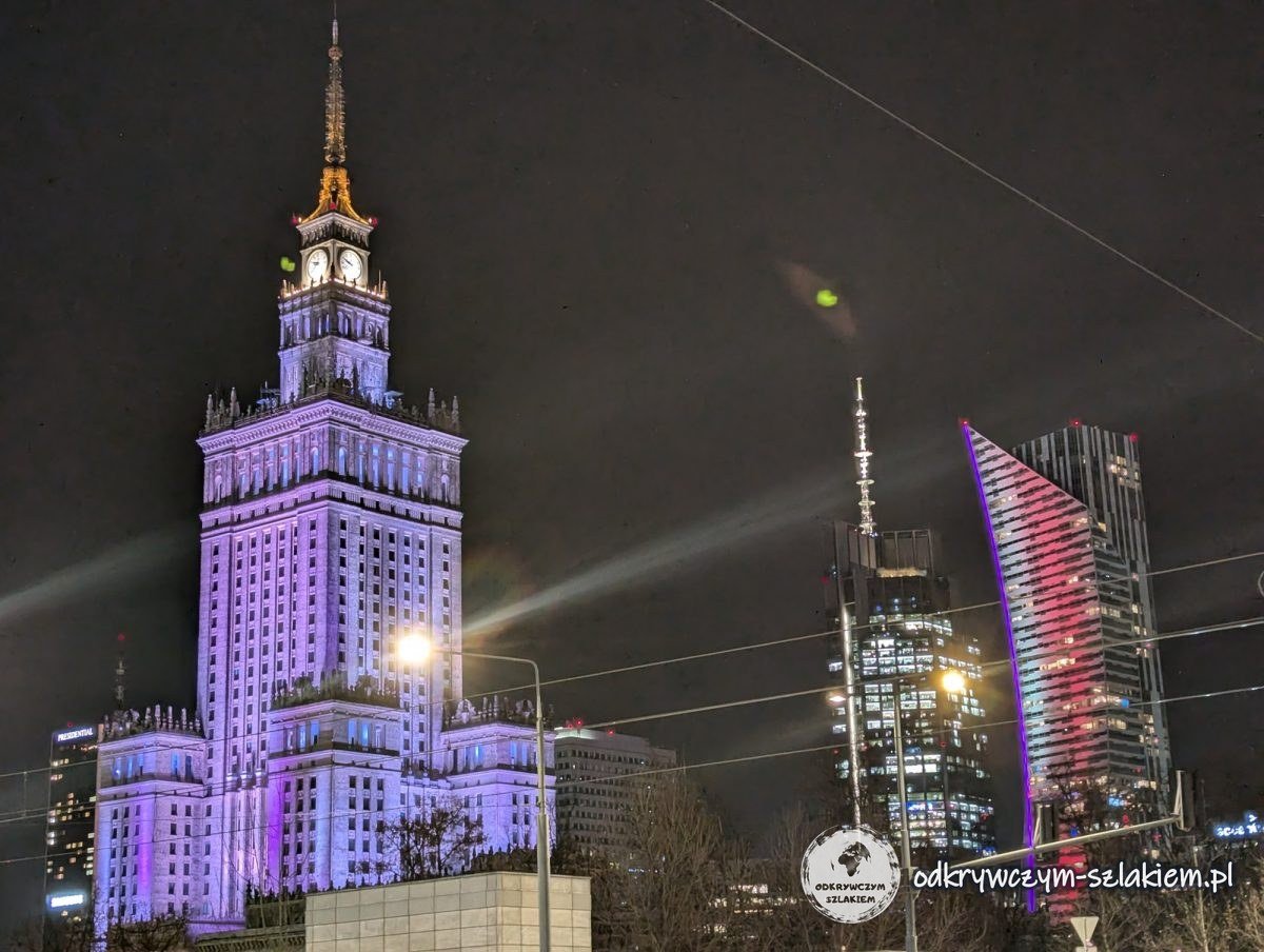 El Palacio de la Cultura y la Ciencia iluminado de morado de noche junto a rascacielos iluminados
