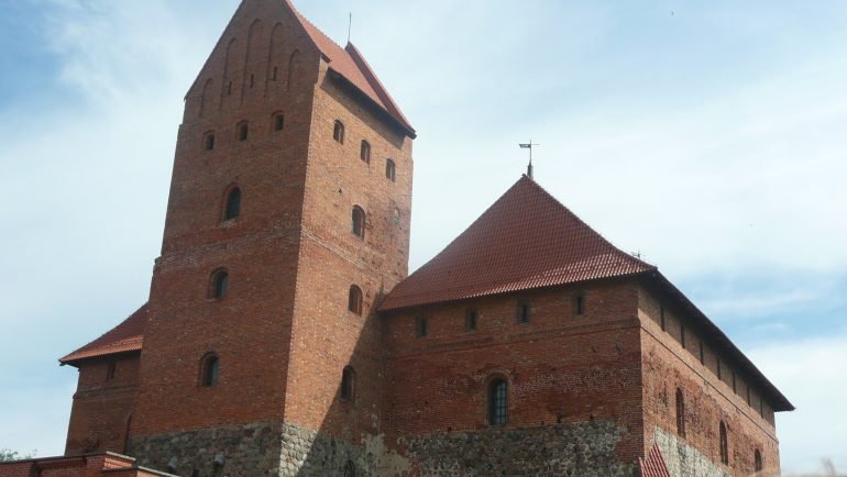 Gotycki zamek na wyspie w Trokach z ceglaną wieżą i czerwonymi dachami