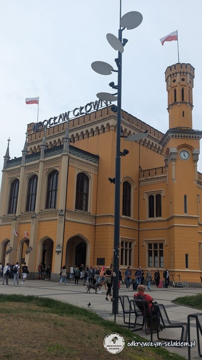 Żółta neogotycka fasada Dworca Wrocław Główny z wieżą zegarową za dnia