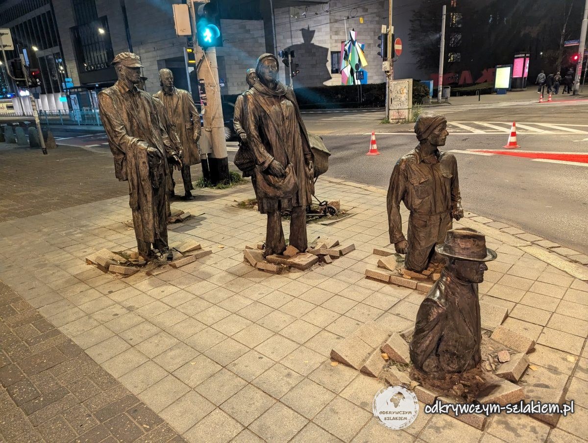 Pomnik Przejście – brązowe postacie przechodniów zapadające się w chodnik i wychodzące z niego nocą
