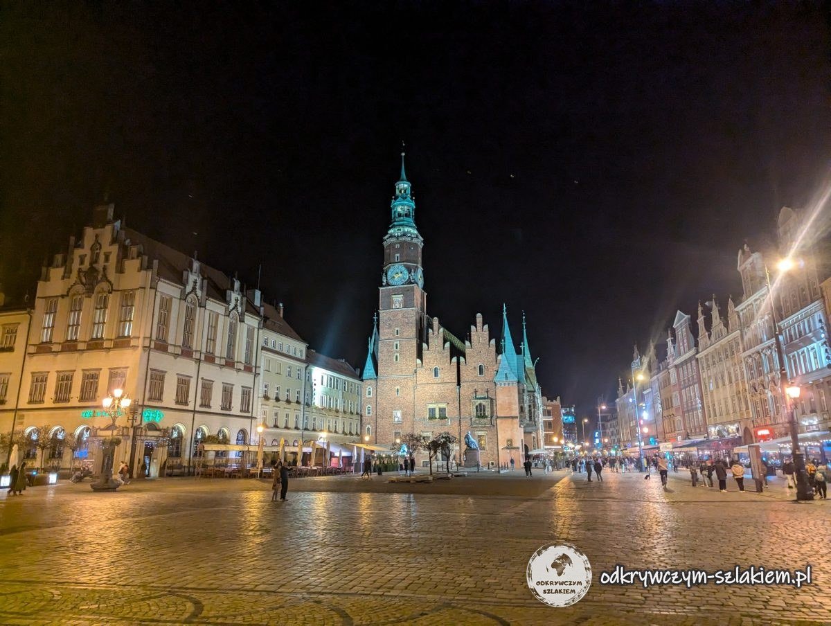 Wrocławski Rynek nocą – kamienice z lokalami i wieża Ratusza w głębi placu