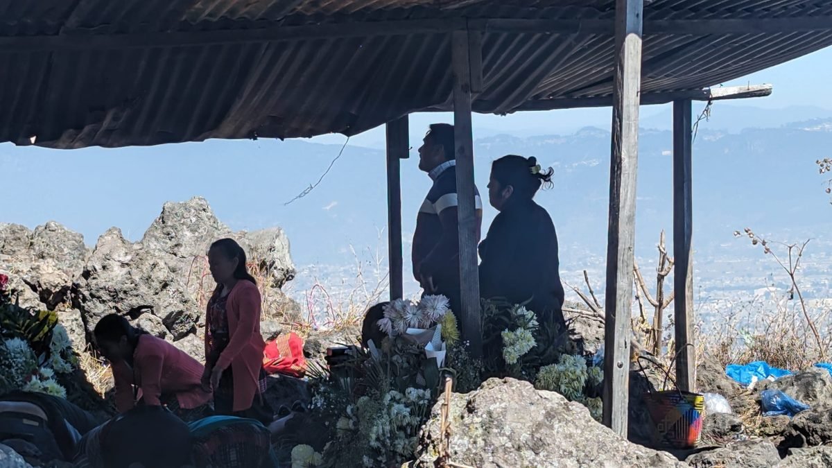 Wierni pod blaszanym zadaszeniem na Cerro Quemado, w tle dolina z Quetzaltenango