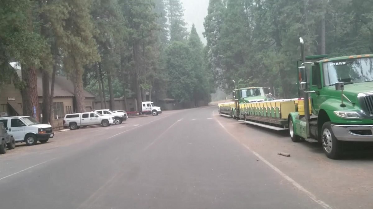 Pusta ulica w wiosce Yosemite z zaparkowanym wagonikiem wycieczkowym, w dymie z pożaru